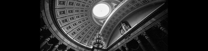 A photo of a dome ceiling with carvings and a skylight.